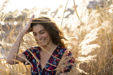 Portrait of a young woman standing in meadow, laughing - AFVF02629