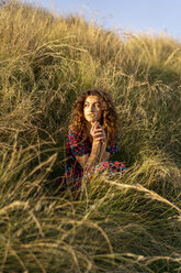 Pensive young woman crouching in meadow - AFVF02632