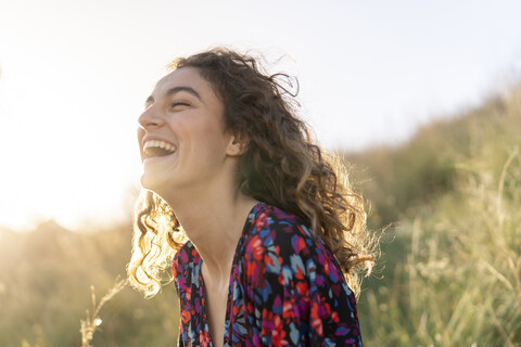 Porträt einer jungen Frau auf einer Wiese stehend, lachend, lizenzfreies Stockfoto