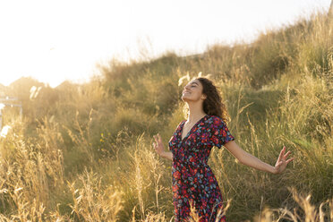 Happy young woman standing in summer meadow - AFVF02639