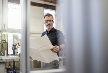 Man in factory holding plan - DIGF06233