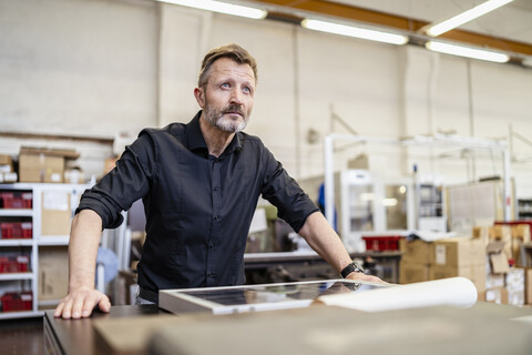 Mann in einer Fabrik bei der Arbeit an einer Solarzelle, lizenzfreies Stockfoto