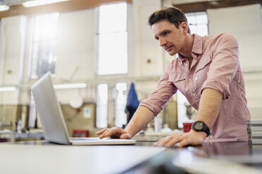 Mann mit Laptop in einer Fabrik - DIGF06261