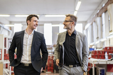 Two smiling businessmen talking in a factory - DIGF06287