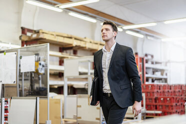 Businessman walking in a factory - DIGF06289