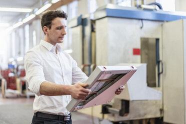 Man in factory holding solar cell - DIGF06291