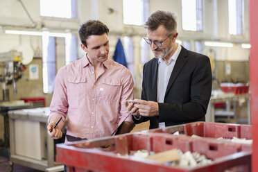 Two men in factory examining workpiece - DIGF06304