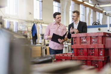 Two men in factory examining workpiece - DIGF06305