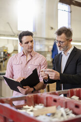 Two men in factory examining workpiece - DIGF06306