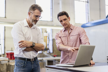 Two colleagues in factory discussing at laptop - DIGF06312