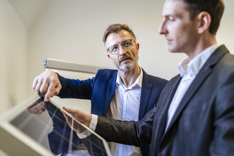 Two businessmen in office with solar cell discussing stock photo