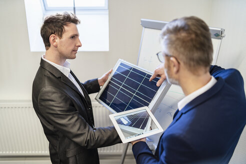 Zwei Geschäftsleute im Büro mit Solarzelle und Tablet diskutieren - DIGF06319