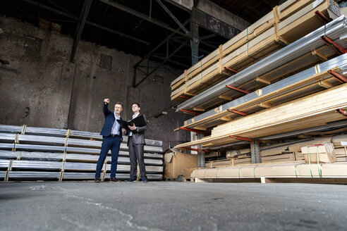 Two businessmen with folder talking in an old storehouse - DIGF06331