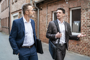 Two businessmen walking and talking at an old brick building - DIGF06334