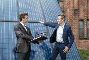Zwei Geschäftsleute unterhalten sich vor einem Backsteingebäude mit Sonnenkollektoren - DIGF06342