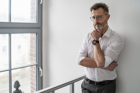 Porträt eines Geschäftsmannes am Fenster im Büro - DIGF06347