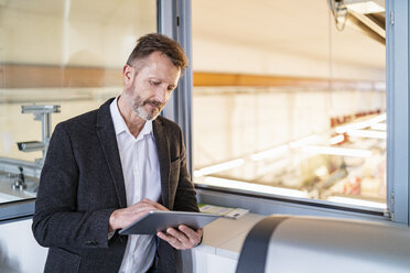 Geschäftsmann mit Tablet am Fenster mit Fabrik Hintergrund - DIGF06355