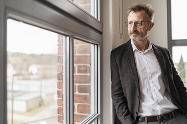 Businessman looking out of window in office - DIGF06361