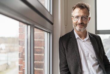 Portrait of confident businessman at the window in office - DIGF06362