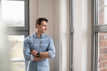 Geschäftsmann schaut im Büro aus dem Fenster - DIGF06363