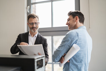 Two colleagues talking at the window in office - DIGF06373