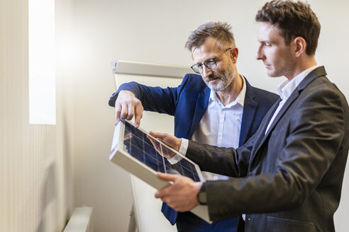 Zwei Geschäftsleute in einem Büro, die über Solarzellen diskutieren - DIGF06379