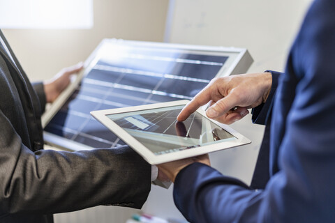 Close-up of two businessmen in office with solar cell and tablet stock photo