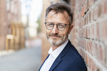 Portrait of confident businessman at brick wall - DIGF06385