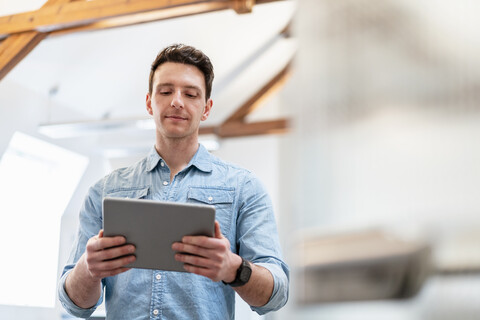 Portrait of young businessman using tablet in office stock photo