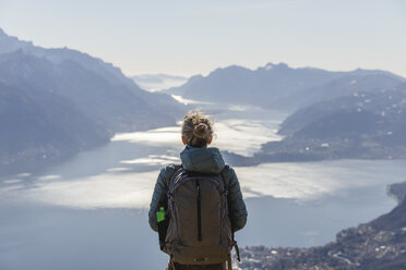 Italien, Como, Lecco, Frau beim Wandern in den Bergen oberhalb des Comer Sees, die die Aussicht genießt - MRAF00371