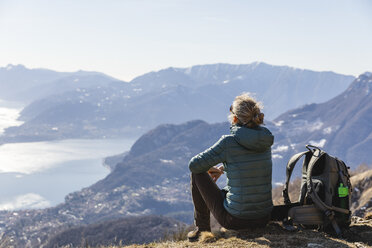 Italien, Como, Lecco, Frau beim Wandern in den Bergen oberhalb des Comer Sees, die die Aussicht genießt - MRAF00373