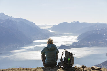 Italy, Como, Lecco, woman on a hiking trip in the mountains above Lake Como sitting down enjoying the view - MRAF00374