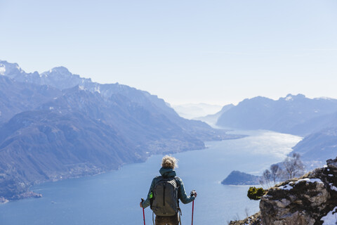 Italien, Como, Lecco, Frau beim Wandern in den Bergen oberhalb des Comer Sees, die die Aussicht genießt, lizenzfreies Stockfoto
