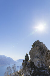 Italien, Como, Lecco, Frau auf Wandertour in den Bergen oberhalb des Comer Sees, auf einem Felsen sitzend und die Aussicht genießend - MRAF00385