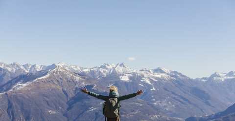 Italien, Como, Frau beim Wandern in den Bergen, die die Aussicht genießt, lizenzfreies Stockfoto
