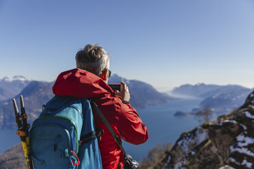 Italy, Como, man on a hiking trip in the mountains above Lake Como taking photo with cell phone - MRAF00397