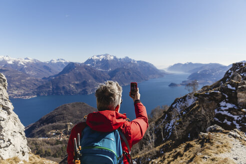 Italien, Como, Mann beim Wandern in den Bergen oberhalb des Comer Sees beim Fotografieren mit dem Handy - MRAF00398
