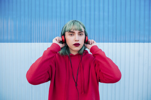 Portrait of young woman with blue dyed hair listening music with headphones - LOTF00063