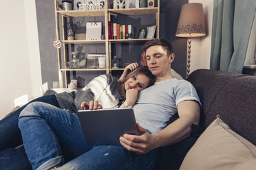 Young couple using tablet on couch at home - SEBF00087