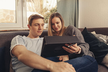 Junges Paar entspannt sich auf dem Sofa und benutzt ein Tablet - SEBF00095