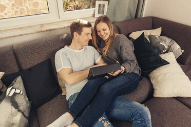 Junges Paar entspannt sich auf dem Sofa und benutzt ein Tablet - SEBF00096