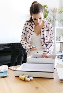 Woman taking colour flasks out of box - MGOF03971