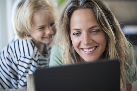 Smiling mother and son at home using tablet stock photo