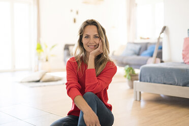 Portrait of smiling woman sitting on the floor at home - SBOF01925