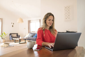Frau benutzt Laptop am Esstisch zu Hause - SBOF01933