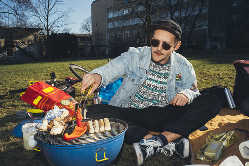 Young man having a barbecue in park - GCF00246