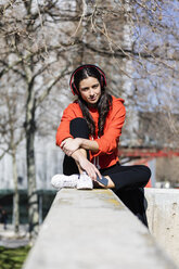 Junge zeitgenössische Tänzerin mit rotem Kapuzenshirt, die sitzt und Musik hört - JRFF02871
