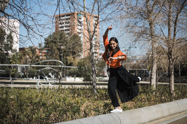 Young contemporary dancer wearing red hoodie shirt, practicing her passion in a park - JRFF02885