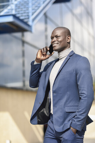 Porträt eines zufriedenen Geschäftsmannes im blauen Anzug am Telefon, lizenzfreies Stockfoto