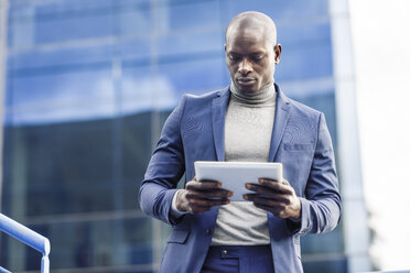 Portrait of smart businessman using digital tablet outdoors - JSMF00886